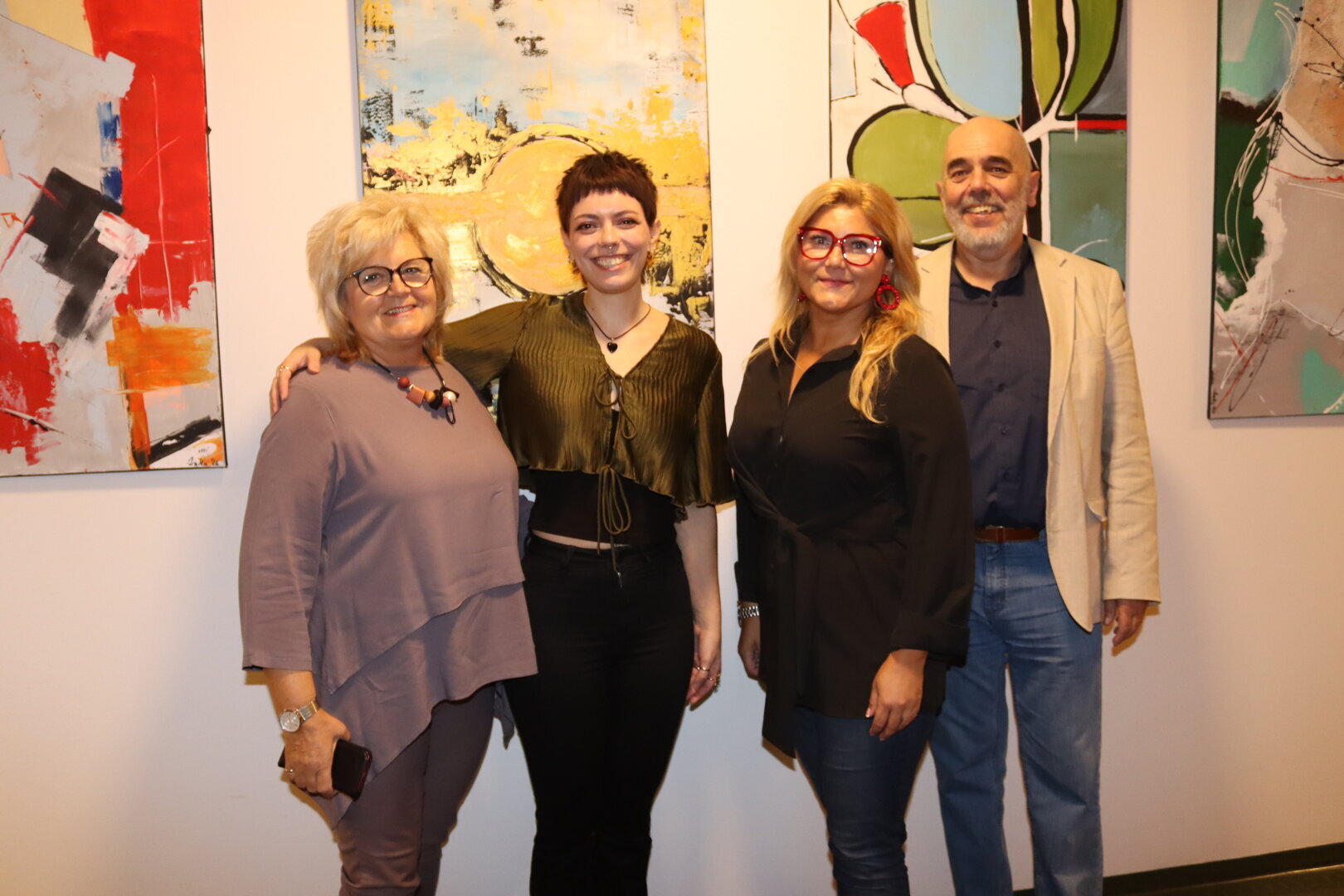 Vier Personen stehen vor abstrakten Bildern in einer Galerie in Wien.